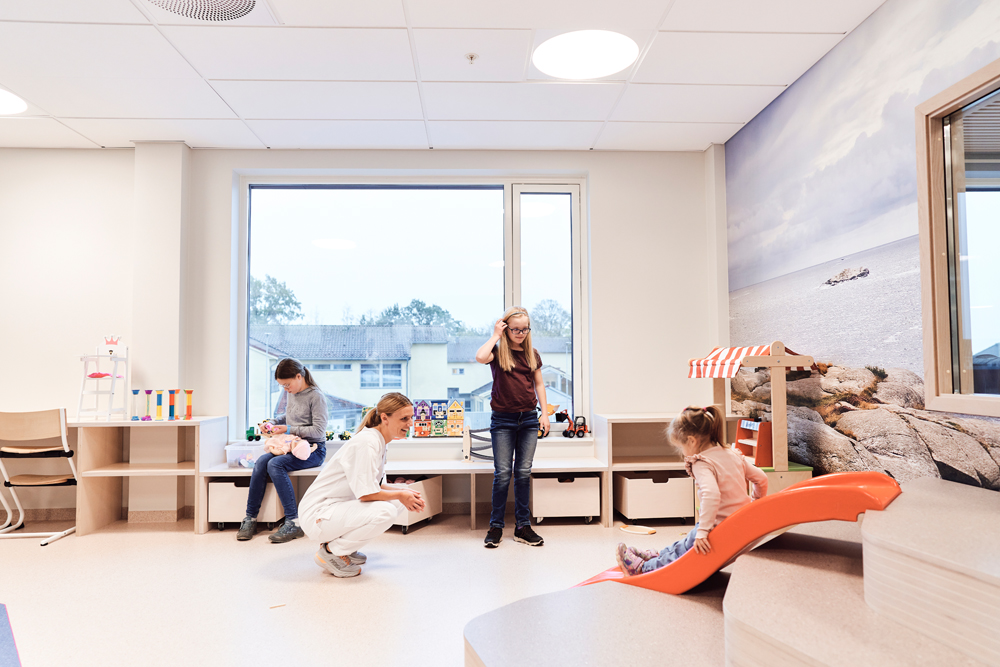 Flere barn og en sykepleier leker i et lekerom