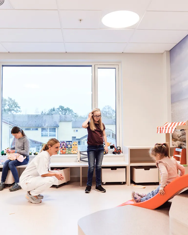 Flere barn og en sykepleier leker i et lekerom