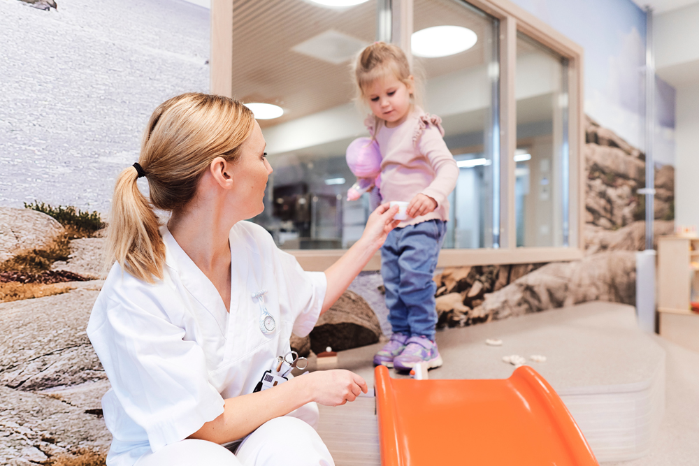 En sykepleier og et lite barn leker