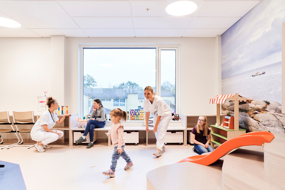 Flere barn og en sykepleier leker i et lekerom