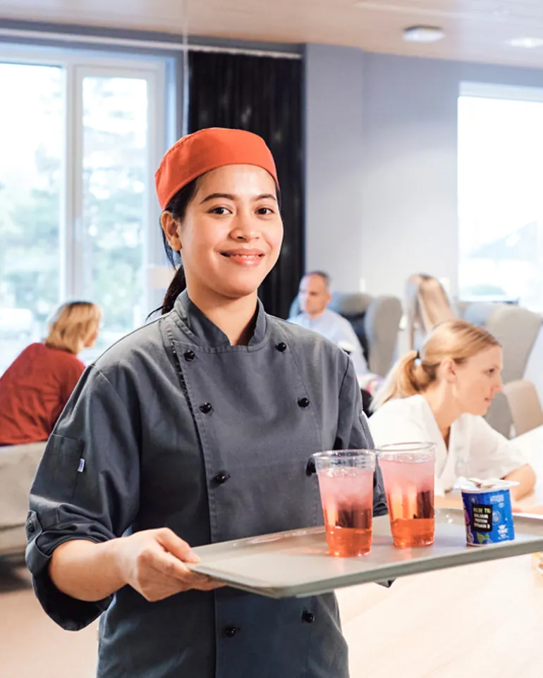 En kantineansatt serverer glass med saft på et brett