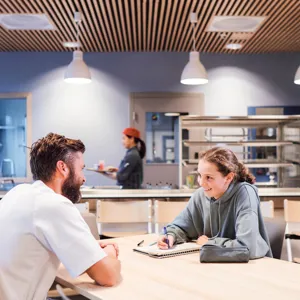 En sykepleier og en jente gjør lekser ved et bord