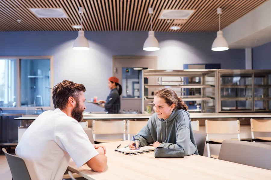 En sykepleier og en jente gjør lekser ved et bord