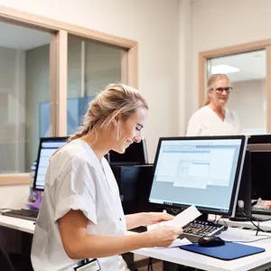 Tre sykepleiere som jobber på et kontor foran datamaskiner