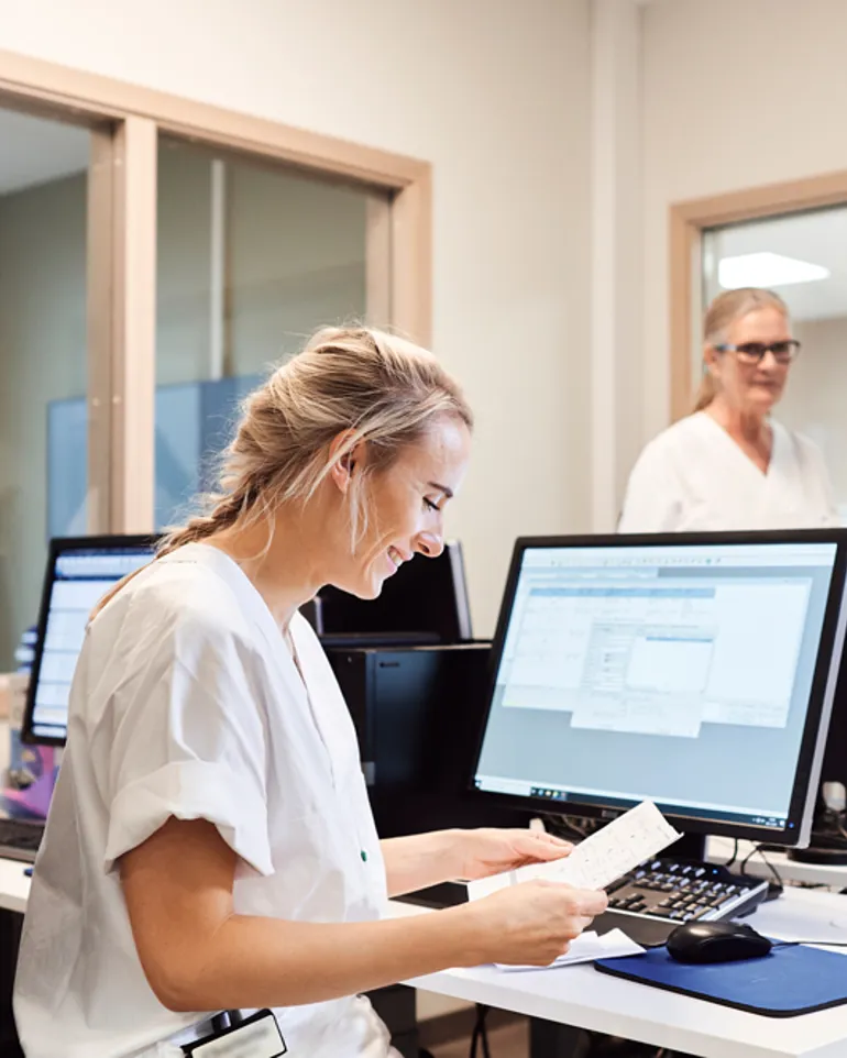 Tre sykepleiere som jobber på et kontor foran datamaskiner