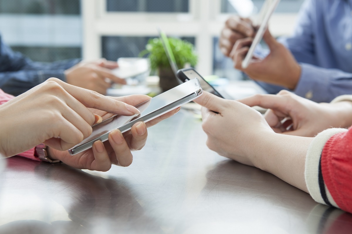 En gruppe mennesker som holder mobiltelefoner