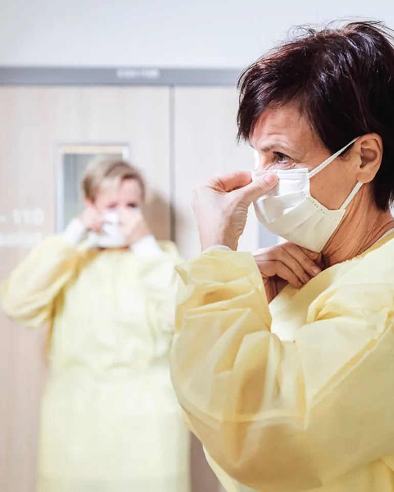 To sykepleiere i smitterverndrakt og munnbind