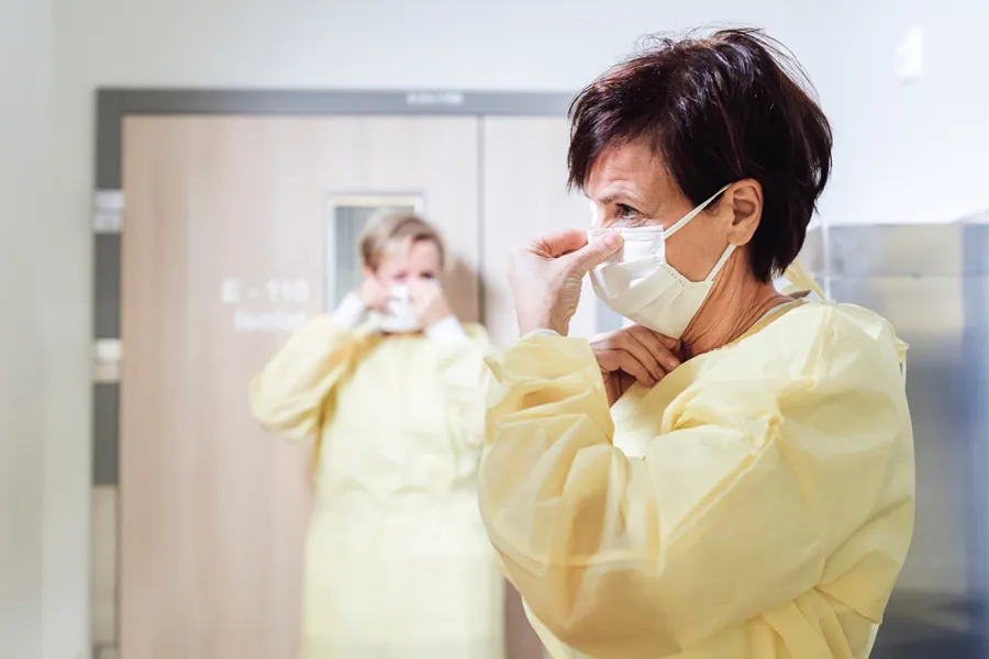 To sykepleiere i smitterverndrakt og munnbind