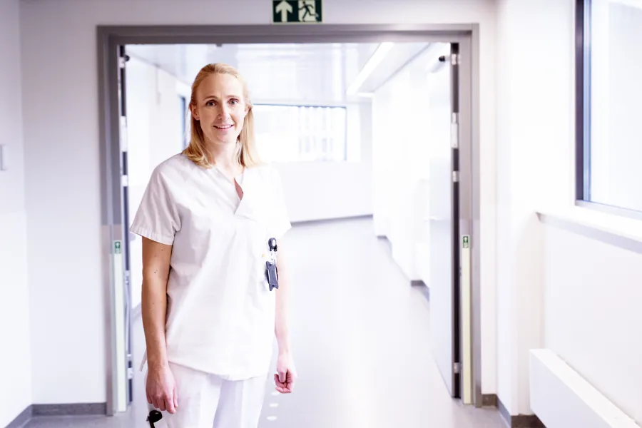 En kvinne i hvit uniform som står i en gang