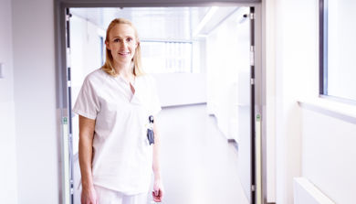 En kvinne i hvit uniform som står i en gang